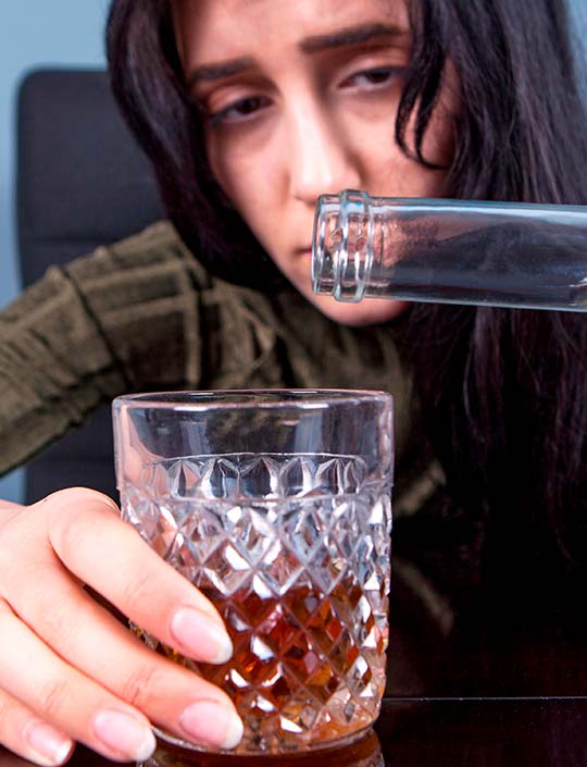 Женщина наливает алкоголь в стакан